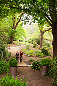 Children walking over wooden bridge in park-like gardens