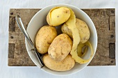 Potatoes and a peeler in a bowl