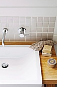 Moderner Waschtisch - Waschbecken mit Holzplatte und Designer Wandarmatur an gefliester Wand