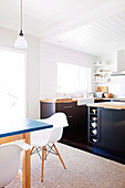 Open-plan kitchen with dark base units and dining area with white shell chairs