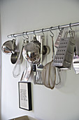 Various kitchen utensils hanging from rod on wall