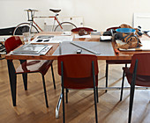Arbeitsutensilien auf Tisch und Stühle im Bauhausstil vor Wand mit geparktem Fahrrad