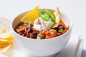 Chili con carne with sour cream and tortilla chips