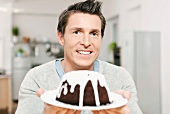 A man serving chocolate cake covered with icing