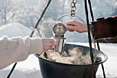 Pärchen kocht Wasser beim Camping im Winter