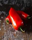 Three red peppers on a wooden surface