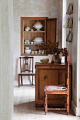 View through floor-to-ceiling doorway of rustic chest of drawers and kitchen chairs in simple dining room