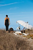Strandidylle mit Frau - Strandplatz am Meer mit aufgespanntem Sonnenschirm