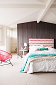 Bedroom with double bed and patterned headboard in front of wooden partition