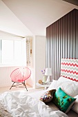 Bed with patterned headboard in front of wooden partition in bedroom