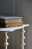 Two hardback books on old wooden shelves with decorative uprights