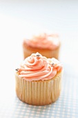 Cupcakes topped with pink frosting and silver balls