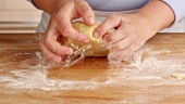 A ball of dough being wrapped in clingfilm