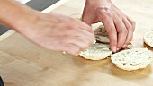 Halved English muffins being spread with butter