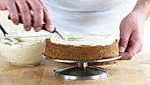 A cake base being spread with cream cheese