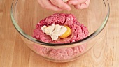 Wrung out softened bread being added to minced meat and an egg