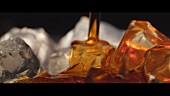Kräuterlikör auf Eiswürfel gießen (Close Up)