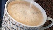 Cappuccino mit heißer Milch aufgiessen