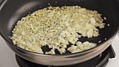 Finely chopped onions and garlic being fried in a pan