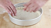Pizza dough being placed in a deep pizza dish