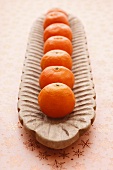 A row of mandarins in a wooden bowl