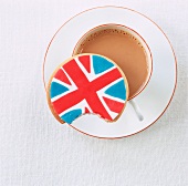 A Union Jack biscuit with a bite taken out balanced on a cup of tea