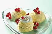 Three scoops of vanilla ice cream with redcurrant and a dollop of cream