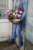 Frau trägt ein Blumenarrangement mit Chrysanthemen