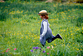 Child running across a meadow of flowers