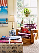 Coffee table with books and antique wicker chair upholstered in colorful fabric in a conservatory