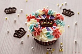 A cupcake topped with cream and a Union Jack surrounded by chocolate crowns