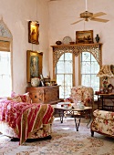 Romantische, antike Sofaecke mit floralen Polstermöbeln und Vintagekommode vor orientalisch verblendetem Sprossenfenster