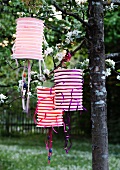 Accordion lanterns decorated with ribbons hanging from tree