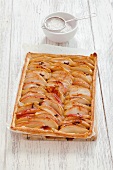 A whole apple and cinnamon tart with icing sugar