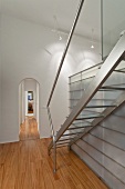 Treppe aus Edelstahl neben Einbau aus Glas Stahl-Konstruktion in Wohnraum mit Rundbogen in traditonellem Flair