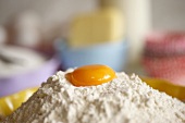 An egg yolk on top of a pile of flour