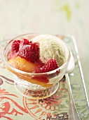 An ice cream sundae with vanilla ice cream, raspberries and peaches