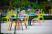 Cafe with outdoor seating - tables and multi-coloured garden chairs on gravel surface