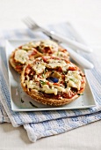A bagel topped with mushrooms, tomatoes and cheese