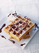 Waffles with chocolate sauce and icing sugar