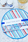 Cutlery and a card on a ribbon on a striped plate