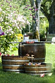Paper boats as garden party decorations on miniature ponds in wooden barrels