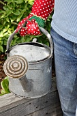 A woman with a watering can in a garden