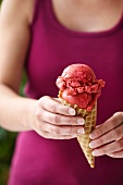 A young woman holding a cone of berry ice cream
