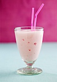 A strawberry smoothie in a glass with straws
