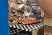 Sausages on a barbecue against a stone wall