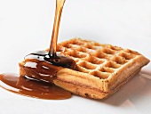 Maple syrup being poured on to waffle