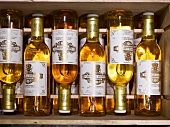 Stickered white wine bottles in a wooden crate (seen from above)