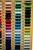 Spools of thread in various colours arranged in rack