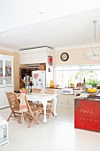 Dining area with antique table and modern garden chairs in open-plan kitchen